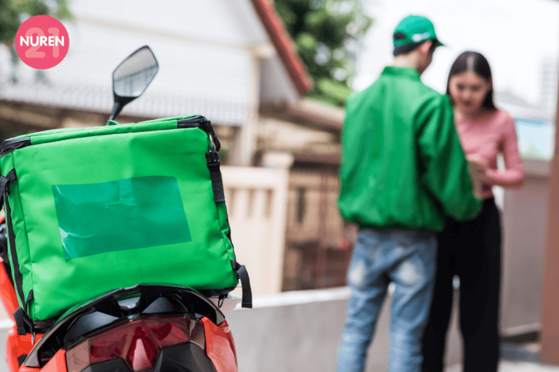 image of woman ordering food delivery motorcyle in green with delivery rider in green jacket and cap