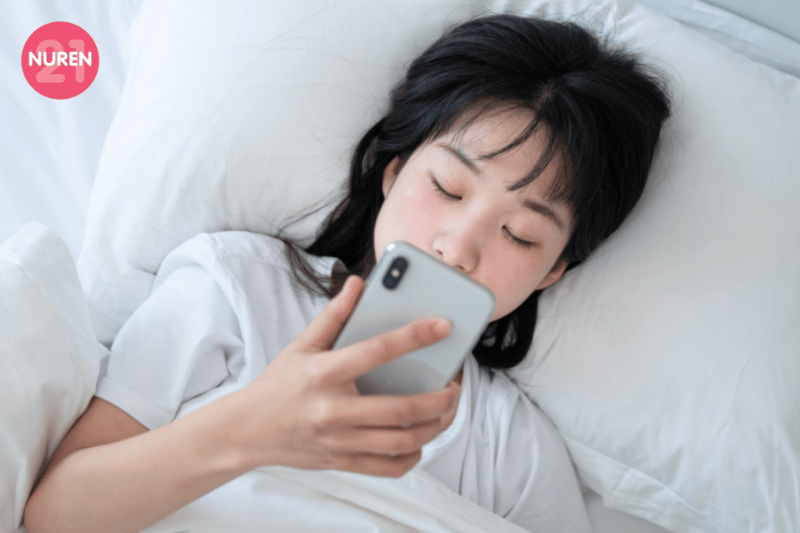 girl in bed looking at phone feeling left out of social events resting and doom scrolling