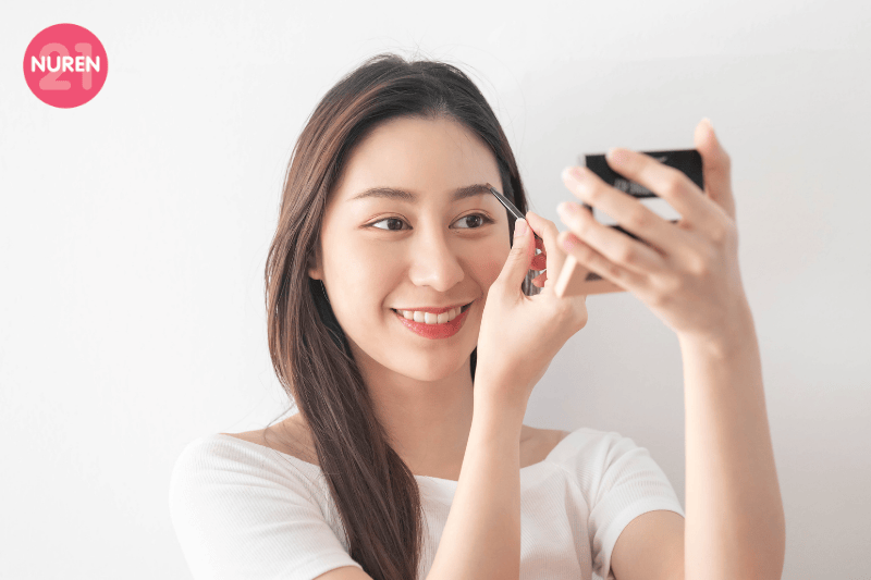 image of women putting on brow gel while looking at compact mirror and smiling