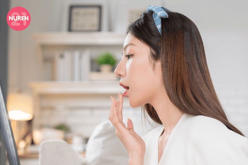 image of young woman patting lipstick on lips while checking on the mirror
