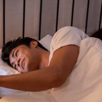 Asian man secretly chatting to mistress while lying in bed with girlfriend. Attractive disloyal husband using phone communicate with paramour lover while his wife sleeping late at night in bedroom.