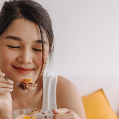 girl holding a yogurt bowl and enjoying some toppings like nuts and fruits