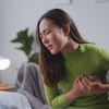 woman experiencing stomach pain wearing green shirt