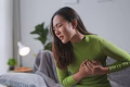 woman experiencing stomach pain wearing green shirt