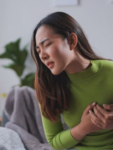 woman experiencing stomach pain wearing green shirt