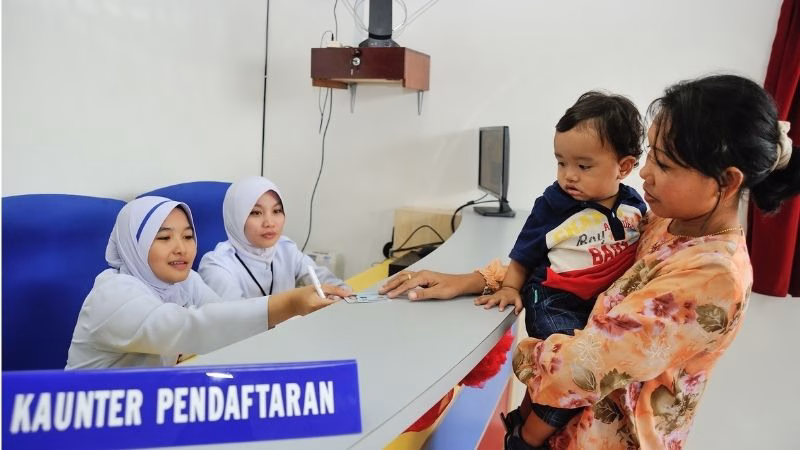 mum and son waiting at registration counter at government clinic malaysia