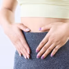woman holding tummy showcasing pcos or pmos