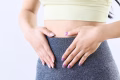 woman holding tummy showcasing pcos or pmos