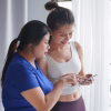 Asian women friends use phone after exercise.
