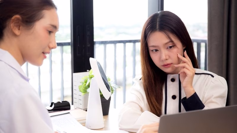 Young asian patient woman consulting with doctor in coat about wrinkle and skin for rejuvenate and beauty while watching laptop in modern medical office, doctor explaining and diagnostic facial.