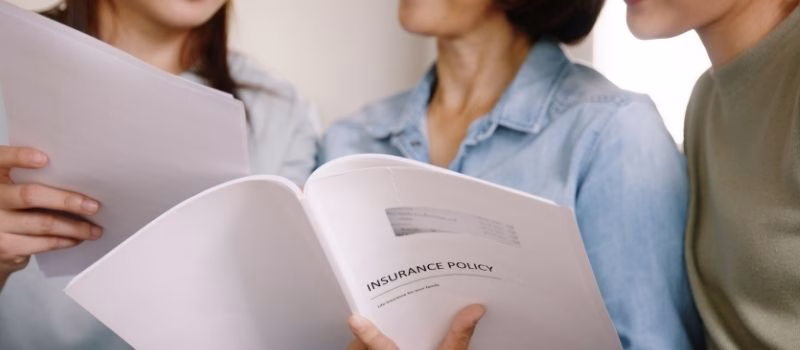 Buy mediclaim health care life insure for older mum. Young adult woman asia people grown up child give gift to middle aged mom reading protect cover saving plan paper smile laugh sitting at sofa home.