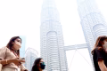 People wearing face mask walking infront of Kuala Lumpur Twin Tower surrounding by haze.