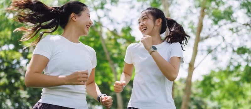 Two happy friends jogging outdoors, enjoying a healthy lifestyle and strong companionship, feeling energetic and positive