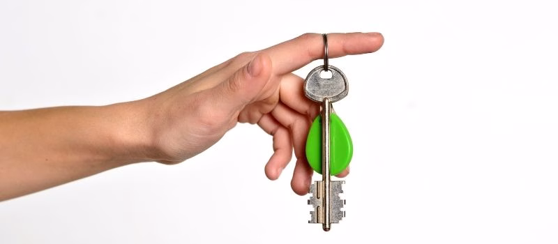 House key with trinket house in the female palm. Rental estate. Sale property template.