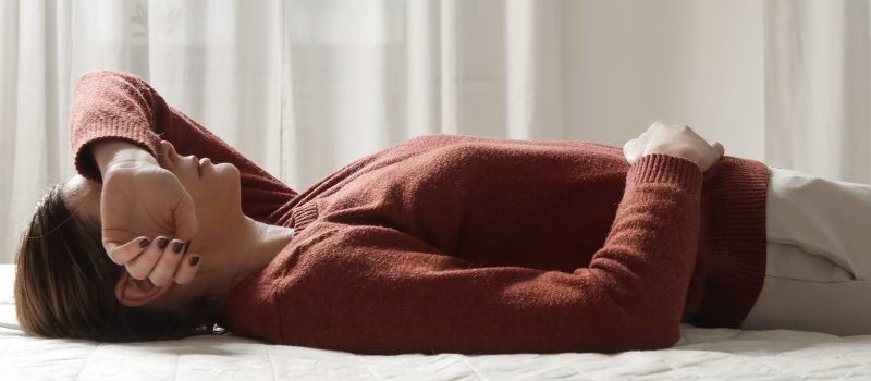 Tired, Sad, Exhausted Woman in Bed Covering Face with Hand – Depression, Insomnia, Perimenopause Fatigue and Emotional Distress, Stress, Burnout and Depression Concept